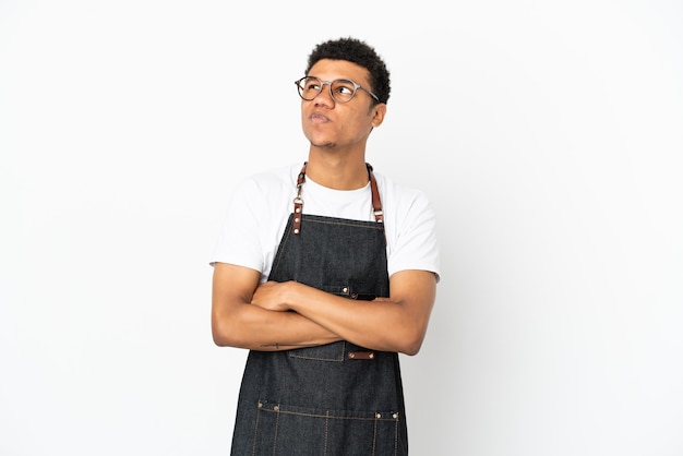 Restaurant Afro-Amerikaanse ober man geïsoleerd op een witte achtergrond die twijfels gebaar maakt terwijl hij de schouders opheft