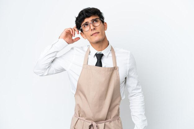 Restaurant Argentinian waiter isolated on white background having doubts and with confuse face expression