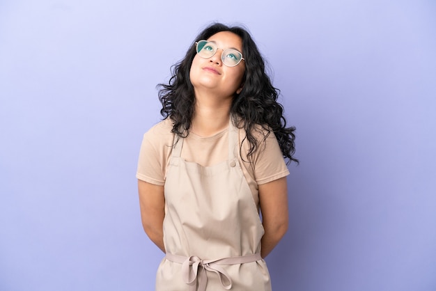 Restaurant asian waiter isolated on purple background and looking up