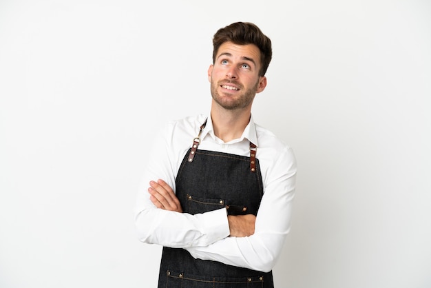 Restaurant caucasian waiter isolated on white background looking up while smiling