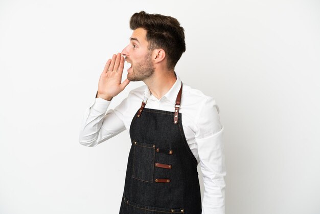 Restaurant caucasian waiter isolated on white background shouting with mouth wide open to the lateral