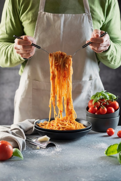 Restaurant concept. Mens die Italiaanse spaghetti met tomaat en basilicum, selectief nadrukbeeld koken