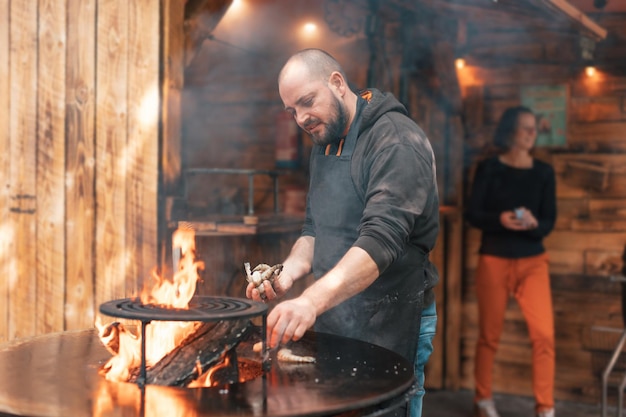 写真 レストランのコック シェフはバーベキューの火で屋外でエビを調理します。