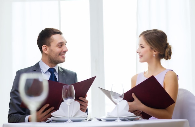 restaurant, couple and holiday concept - smiling couple with menus at restaurant