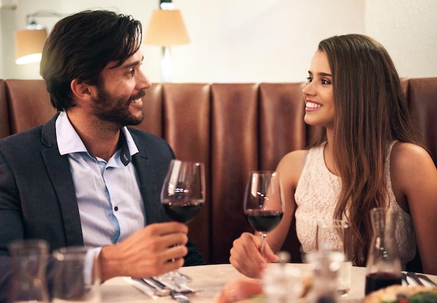 レストランのカップルとバレンタインデーのデートで、ワイングラスの愛と幸せなコミュニケーションを祝い、若い男性と女性が一緒に高級レストランでドリンクを飲み、休日のお祝いにロマンチックなディナーを楽しむ