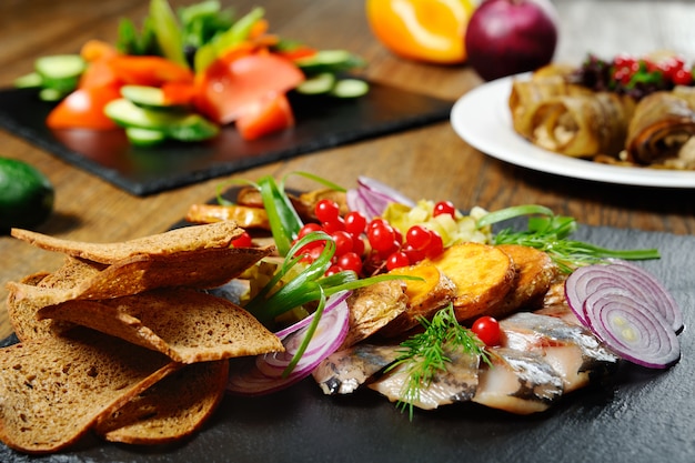 Restaurant dish - baked potatoes with onion rings and herring close-up