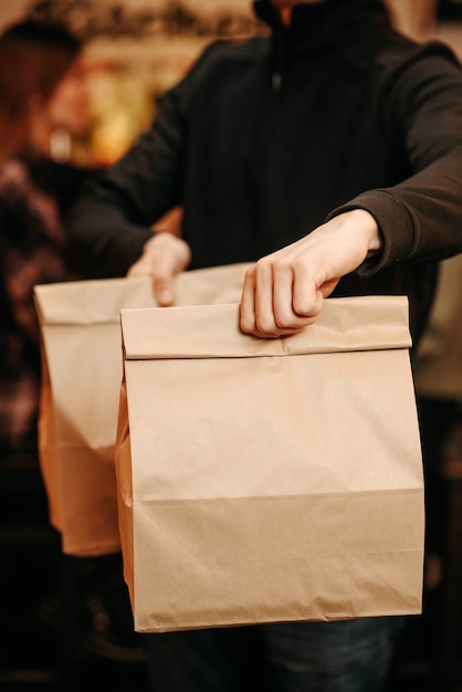 Photo restaurant employee holding takeaway craft bags with food