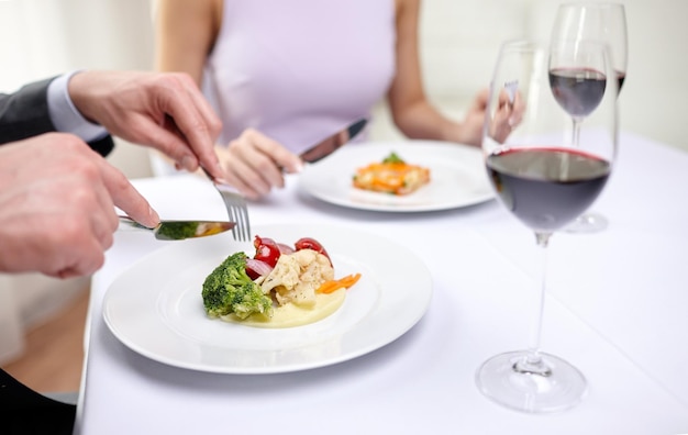 restaurant, food, people, date and holiday concept - close up of couple eating appetizers at restaurant