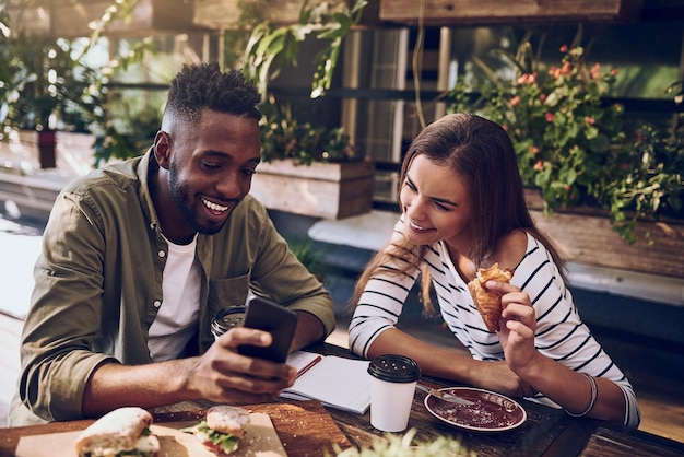 Restaurant gelukkige en zwarte man en vrouw met telefoon voor sociale media internet en online website Coffeeshopcommunicatie en vrienden op smartphone lachen om meme praten en chatten bij het ontbijt