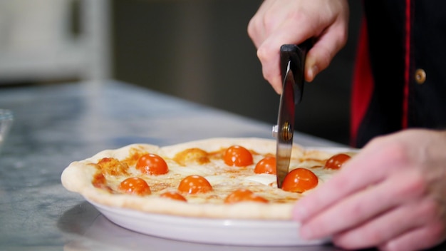 Restaurant kitchen a chef cutting the pizza on pieces