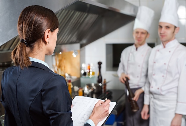 Менеджер ресторана проводит брифинг для сотрудников своей кухни на коммерческой кухне