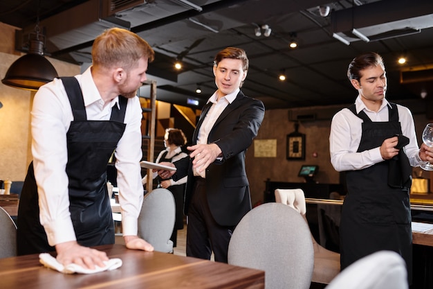 Restaurant manager giving task to waiter during cleanup