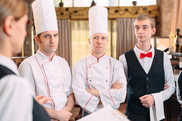 Restaurant manager and his staff in kitchen. interacting to head chef in commercial kitchen.