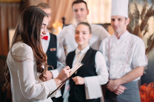 Restaurant manager and his staff in kitchen. interacting to head chef in commercial kitchen.