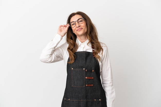 Restaurant middle aged waiter woman isolated on white background with glasses and happy