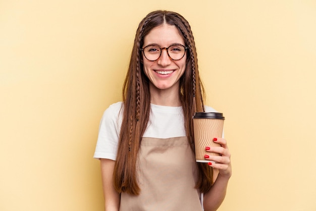 Restaurant ober vrouw met een take-away koffie geïsoleerd op gele achtergrond gelukkig, glimlachend en vrolijk.