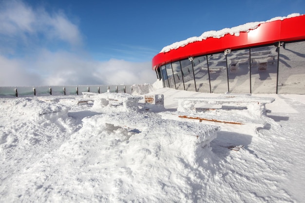 Restaurant open terrace during winter. Heavy snowing caused wooden benches and tables are barely visible under snow load.