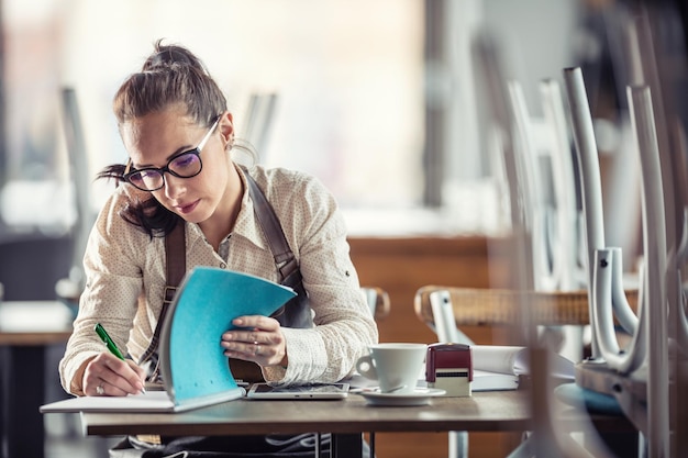 Photo restaurant owner does bills and paperwork after hours over coffee