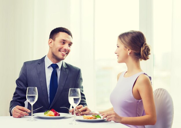 restaurant, paar en vakantieconcept - glimlachend paar dat hoofdgerecht eet bij restaurant