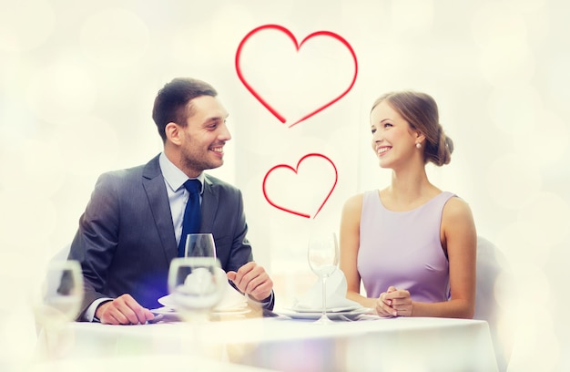 restaurant, paar en vakantieconcept - glimlachend paar die elkaar bij restaurant aankijken