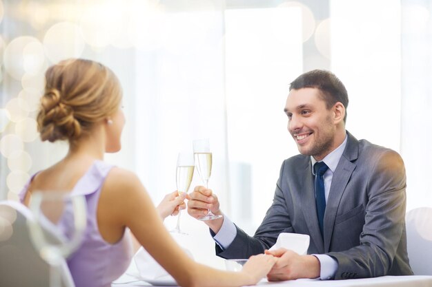 restaurant, paar en vakantieconcept - glimlachende man met glas champagne kijkend naar vrouw of vriendin in restaurant