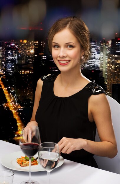 restaurant, people and holiday concept - smiling young woman eating main course at restaurant