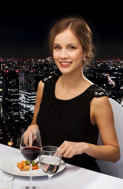 restaurant, people and holiday concept - smiling young woman eating main course at restaurant