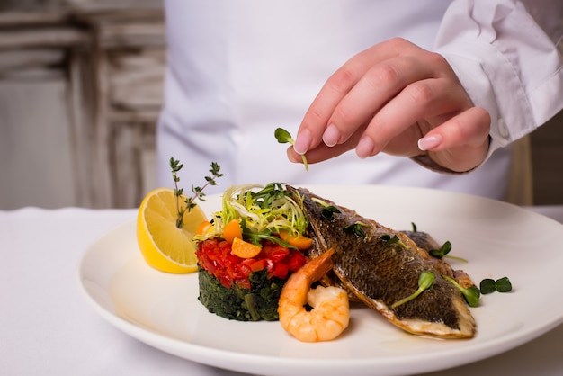 Ristorante con piatti di pesce. cucinare frutti di mare, mano femminile. spazio libero per il testo.