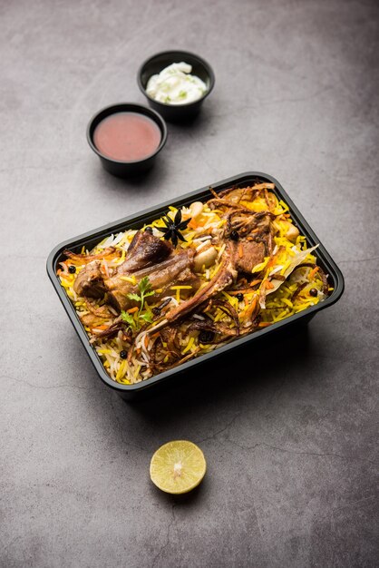 Restaurant style Gosht or Mutton Biryani or Pulao packed for home delivery in plastic box or container with Raita and salan