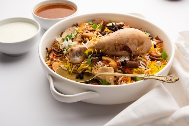 레스토랑 스타일 스파이시 치킨 비리야니는 라이타와 살란, 인기 있는 인도 또는 파키스탄 비채식 요리와 함께 제공됩니다.