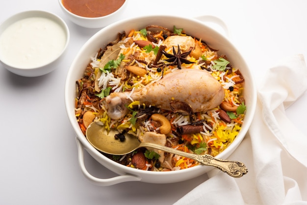 Ресторанный стиль Spicy Chicken Biryani подается с раитой и саланом, популярными индийскими или пакистанскими невегетарианскими блюдами.