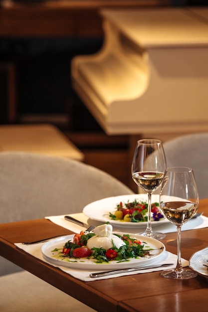 Restaurant table served with salads and glasses of white wine