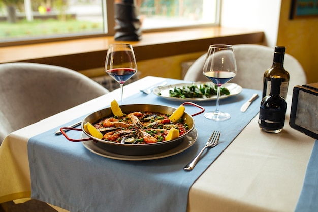 Restaurant table served with spanish dishes seafood paella and padron peppers