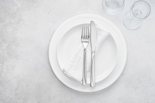 Restaurant table setting with white plates, glasses and cutlery 