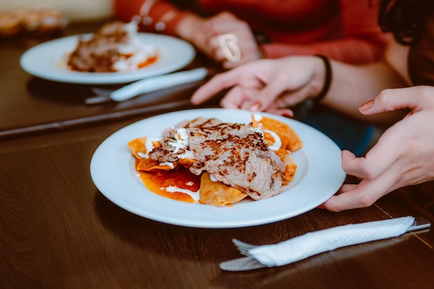 In a restaurant they serve a plate of chilaquiles with cream cheese and red sauce a delicious Mexican dish