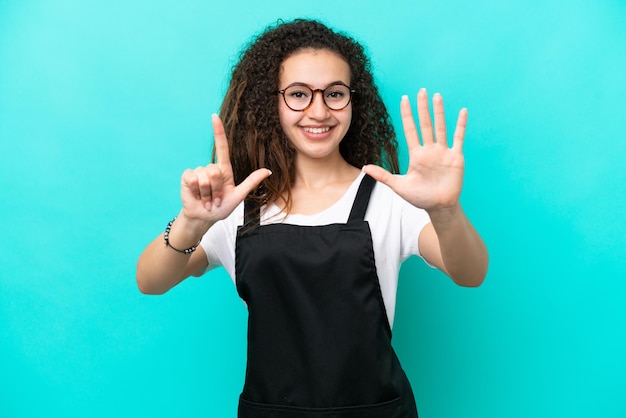 Restaurant waiter Arab woman isolated on blue background counting seven with fingers
