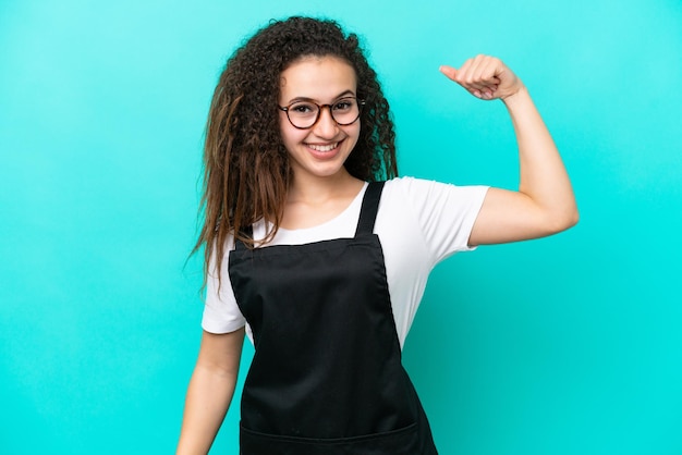 Restaurant waiter Arab woman isolated on blue background doing strong gesture