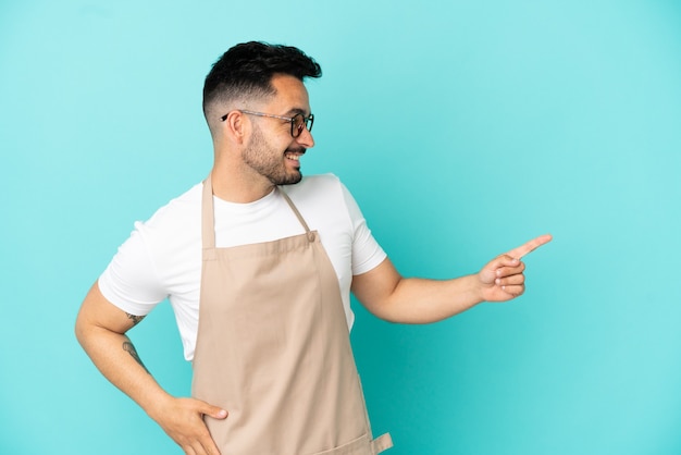 Restaurant waiter caucasian man isolated on blue background pointing finger to the side and presenting a product