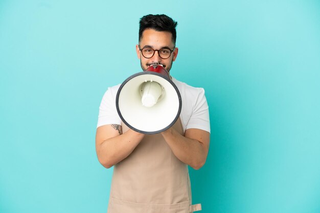 Restaurant waiter caucasian man isolated on blue background shouting through a megaphone