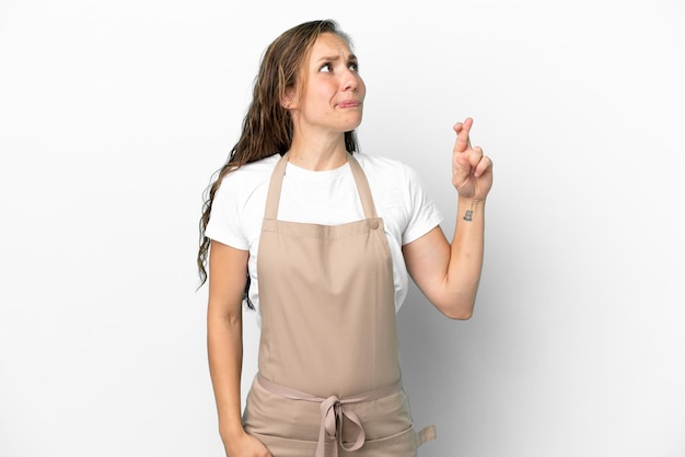 Restaurant waiter caucasian woman isolated on white background with fingers crossing and wishing the best