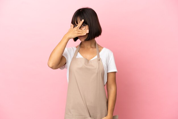 Restaurant waiter over isolated pink background covering eyes by hands and smiling