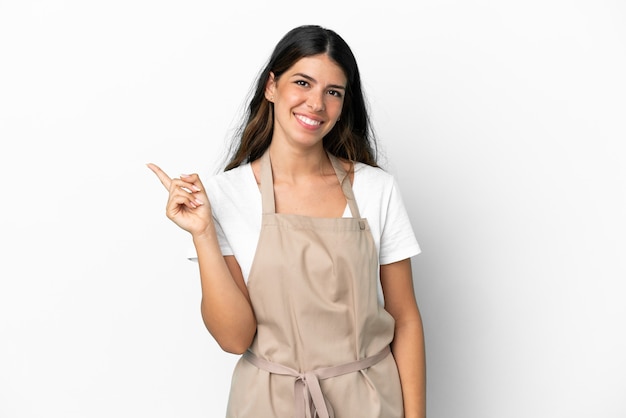 Restaurant waiter over isolated white background pointing to the side to present a product