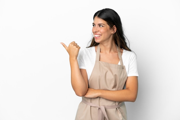 Restaurant waiter over isolated white background pointing to the side to present a product