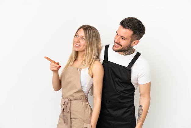 Restaurant waiter over isolated white background pointing to the side to present a product