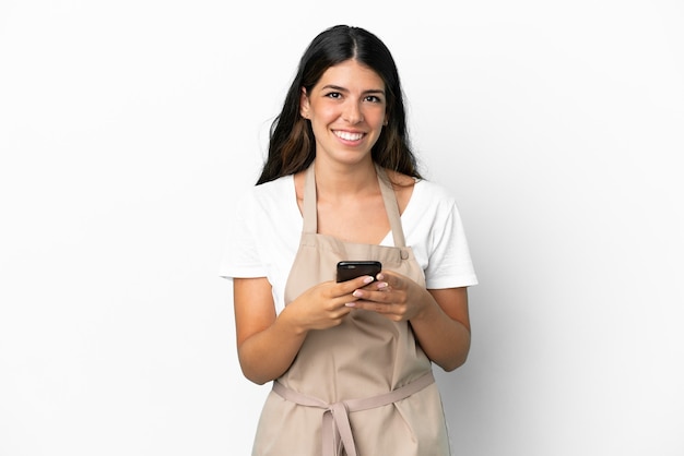 Restaurant waiter over isolated white background sending a message with the mobile