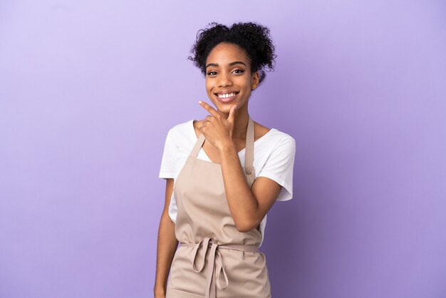 Restaurant waiter latin woman isolated on purple background happy and smiling