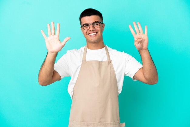 Restaurant waiter man over isolated blue background counting nine with fingers