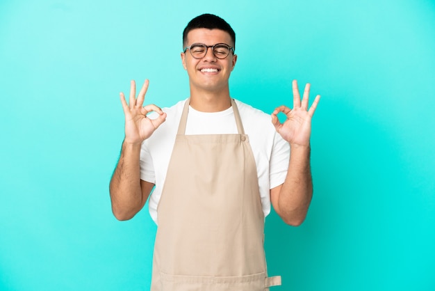 Restaurant waiter man over isolated blue background in zen pose