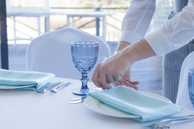 Il cameriere del ristorante serve una tavola per una celebrazione di nozze, primo piano