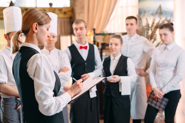 Restaurantmanager en zijn personeel in keuken. interactie met de chef-kok in de commerciële keuken.